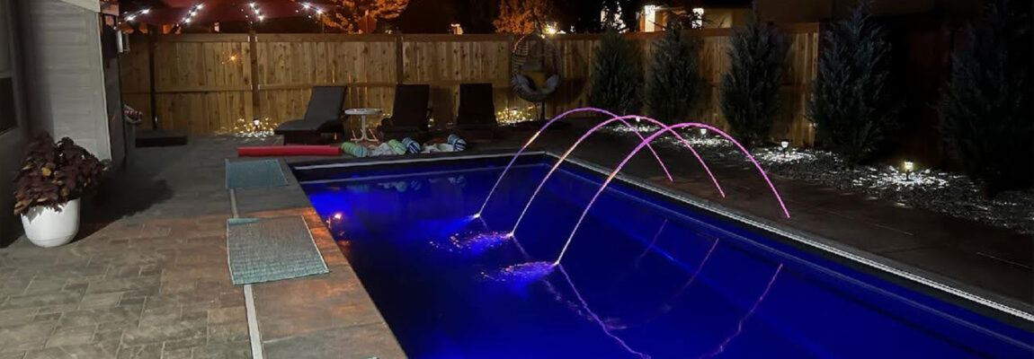 LED lighted deck jets illuminating a fiberglass pool at night in Boise Idaho backyard